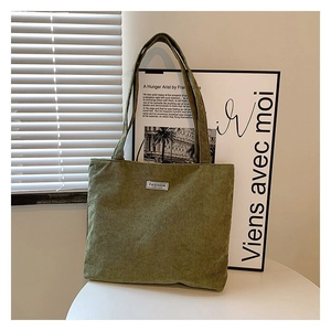 Close-up of green corduroy tote bag texture with fashion label and artistic background