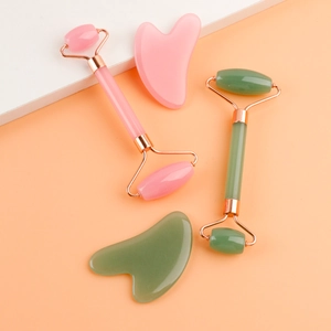 Close-up of pink and green resin face rollers and heart-shaped gua sha massage tools