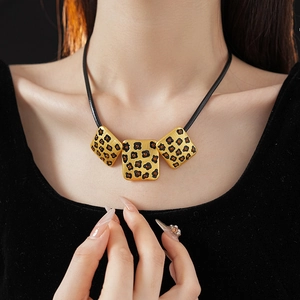 Close-up of a vintage leopard print necklace with a gold square pendant on a model
