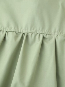 Detail shot of light grass green woven fabric showing delicate pleated craftsmanship