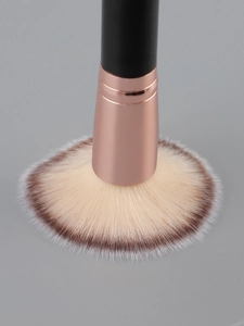 Detailed macro of professional makeup brush with soft dual-tone bristles and golden ferrule