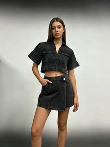 Detail view of the washed black denim fabric and asymmetrical hemline of the skirt