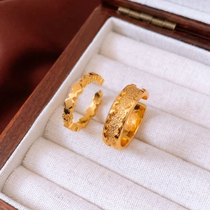 Detailed shot of two 24k gold plated open rings with textured heart and wave patterns