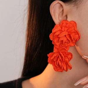 Close-up of model wearing vibrant orange fabric multi-layered rose flower earrings