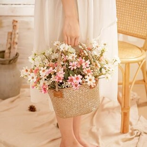Detail of hand-woven flower basket with colorful faux daisies and round handle