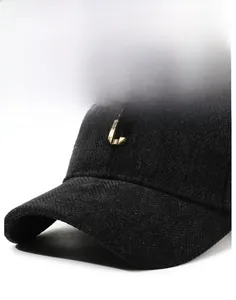 Close-up of black herringbone wool baseball cap with a golden metal letter C logo