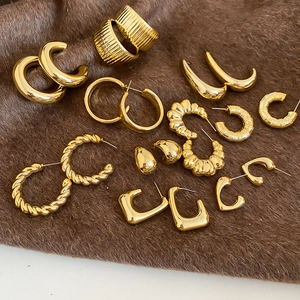 Detailed flat lay of assorted minimalist gold earrings on a dark brown plush fabric surface