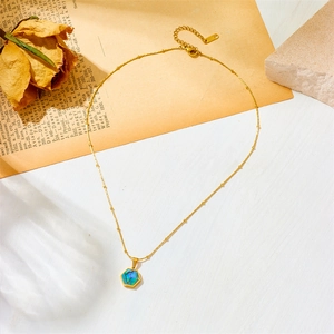 Minimalist gold titanium necklace with hexagonal abalone shell pendant on vintage background