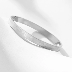 Minimalist silver stainless steel oval bangle featuring engraved zodiac signs for couples