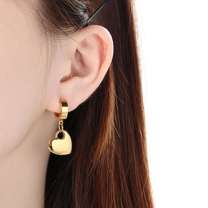 Close-up of golden hollow heart earrings on model with high-polish finish details