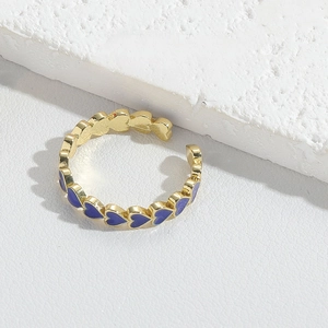 Detail of adjustable gold ring featuring blue enamel hearts on a textured surface