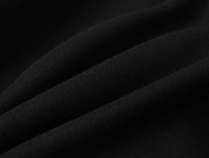 Detailed macro view of black wool blend fabric texture on short double-breasted coat