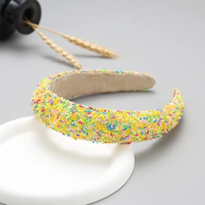 Detail of yellow wide headband with colorful glitter candy sprinkles on a white tray