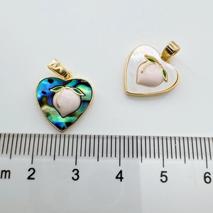 Detail view of heart peach pendants with shell inlay and scale for size measurement