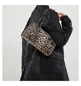 Detailed view of leopard print baguette shoulder bag styled with a black coat