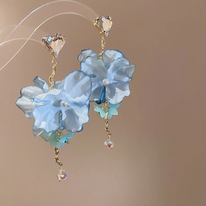 Close-up of blue chiffon flower earrings with crystal heart studs and pearl accents