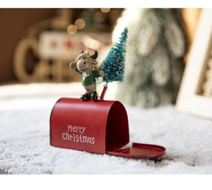 Close-up of red metal Christmas mailbox with cute reindeer doll and mini tree decoration