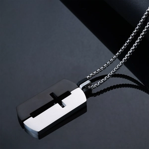 Détail macro du pendentif croix évidée bicolore noir et argent en acier inoxydable brossé