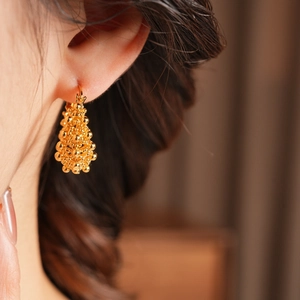 Vue macro de boucles d'oreilles créoles dorées 18k avec pendentif goutte perlé