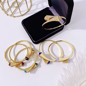 Macro shot of gold bangles with pyramid accents and colorful crystals in a display box