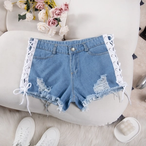 Dettaglio di pantaloncini in denim azzurro con lacci laterali e orlo con frange