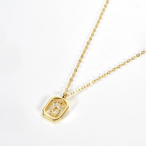 Detail of a gold S925 silver necklace with a geometric pendant and sparkling zircon stone