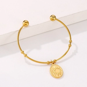 Détail du pendentif soleil et lune doré sur le bracelet jonc réglable en acier