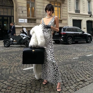 Robe en satin léopard à col en V et dos nu portée avec un manteau en fourrure blanche en rue