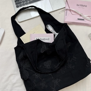 Macro detail of intricate black butterfly lace embroidery on a high-capacity tote bag