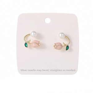 Detail of pink tulip earrings with green leaves, white pearl accents and gold plating