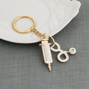 Golden stethoscope and syringe keychain with white enamel on a white embossed plate