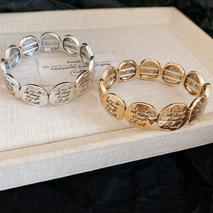 Detail of gold and silver elastic bracelets with engraved religious inspirational text