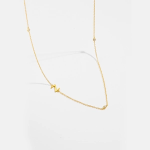 Detail of gold necklace with a minimalist letter Z pendant and three clear cubic zirconia stones