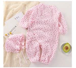Pink floral cotton gauze baby romper with matching sun hat on a minimalist table