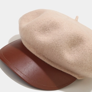 Detailed view of the wool body and brown leather brim on the baker boy cap