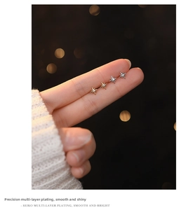 Close-up of s999 silver eight-pointed star stud earrings with zircon on finger