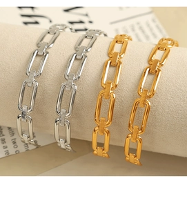 Detailed macro view of 18K gold and silver plated paperclip chain bracelets on fabric