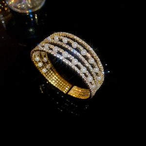 Detail of multi-layer gold bangle with pavé crystals and elegant white pearls