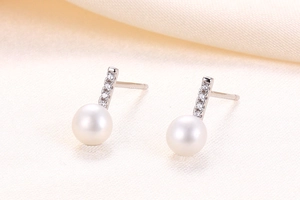 Detailed view of large white pearl stud earrings on satin with sparkling zircon row