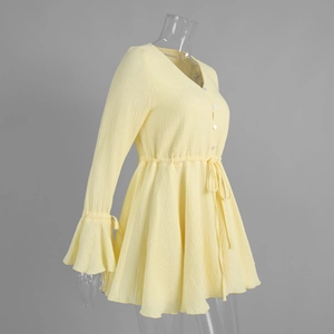 Detail of yellow cotton dress showing V-neck, white buttons and bell sleeve texture