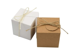 Detail of square kraft and white gift boxes with twine bow and scalloped edge label