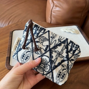 Close-up of handmade linen pouch with blue floral embroidery and simple wish label