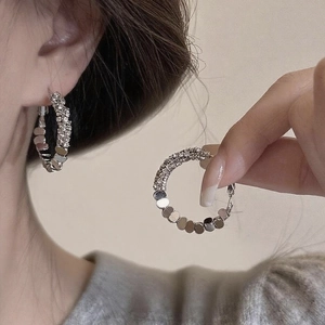 Detail of silver geometric hoop earrings featuring half crystal pavé and metal discs
