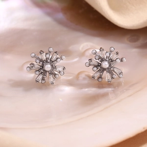 Detailed view of silver snowflake earrings with pearls and zircon in a shell