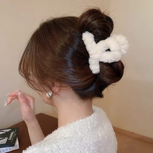 Detail of white plush claw clip shown on model's hair for autumn and winter styling