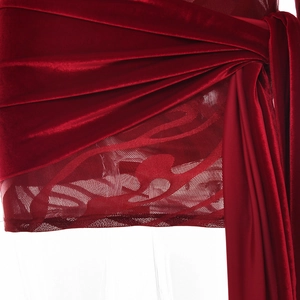 Dettaglio dell'abito in velluto rosso con lacci laterali e bordo in pizzo a fiori