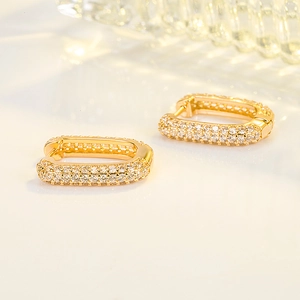 Orecchini geometrici a U in oro con pavé di zirconi bianchi su uno sfondo pulito