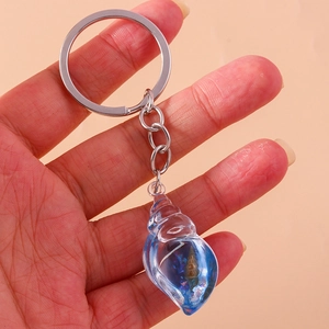 Close-up of a luminous blue resin conch keychain with a real shell and silver metal ring