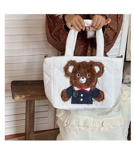 Detail of white quilted handbag featuring a cute brown teddy bear plush patch embroidery