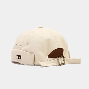 Detailed macro view of beige docker cap with vintage bear embroidery and canvas texture
